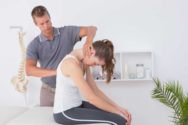 A person standing up and stretching in a sunlit living room with relaxed posture and visible comfort.
