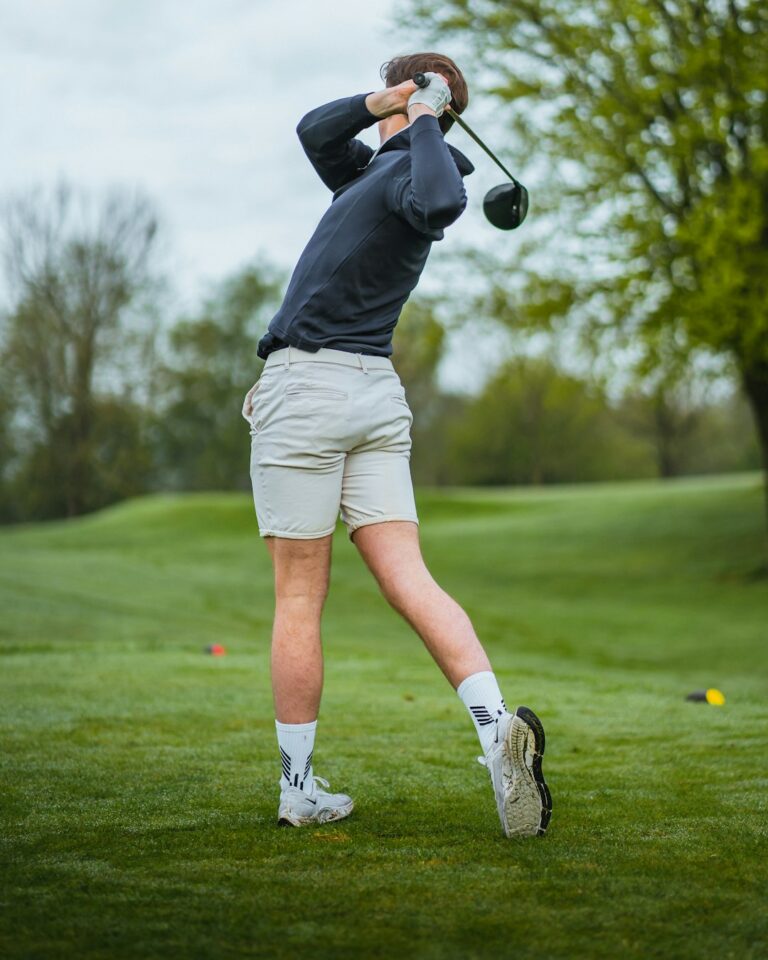 Golfer performing a controlled trunk rotation stretch beside a golf bag before practice.